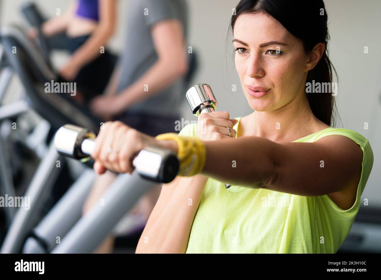 Giovane bella donna facendo esercizi con pesi nella palestra Foto Stock