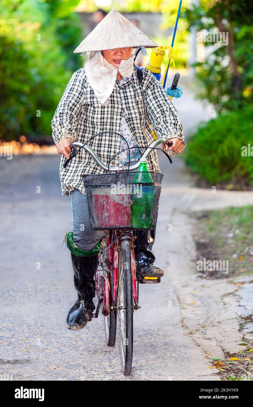 Ciclista che indossa cappello di bambù sulla strada di campagna, rurale Hai Phong, Vietnam Foto Stock