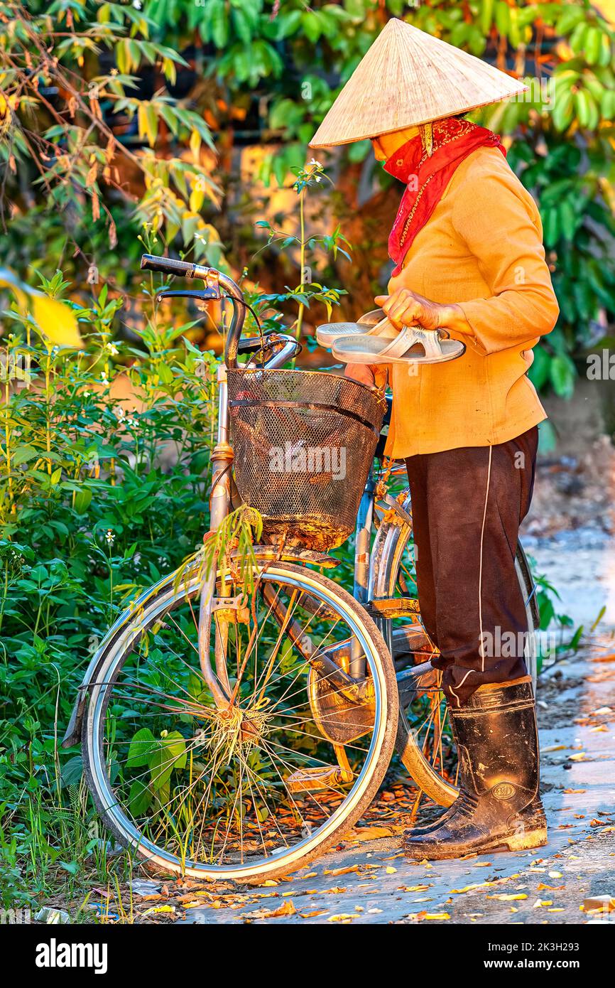 Contadino vietnamita in bicicletta con cappello di bambù nella campagna di Hai Phong, Vietnam Foto Stock