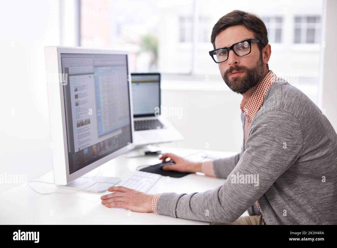 Progettazione di successo. Un bel giovane uomo alla sua scrivania in un ufficio. Foto Stock