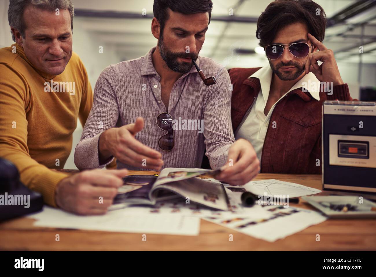 Questo potrebbe funzionare... tre designer rivestiti di abbigliamento retrò 70s che lavorano insieme a un progetto. Foto Stock