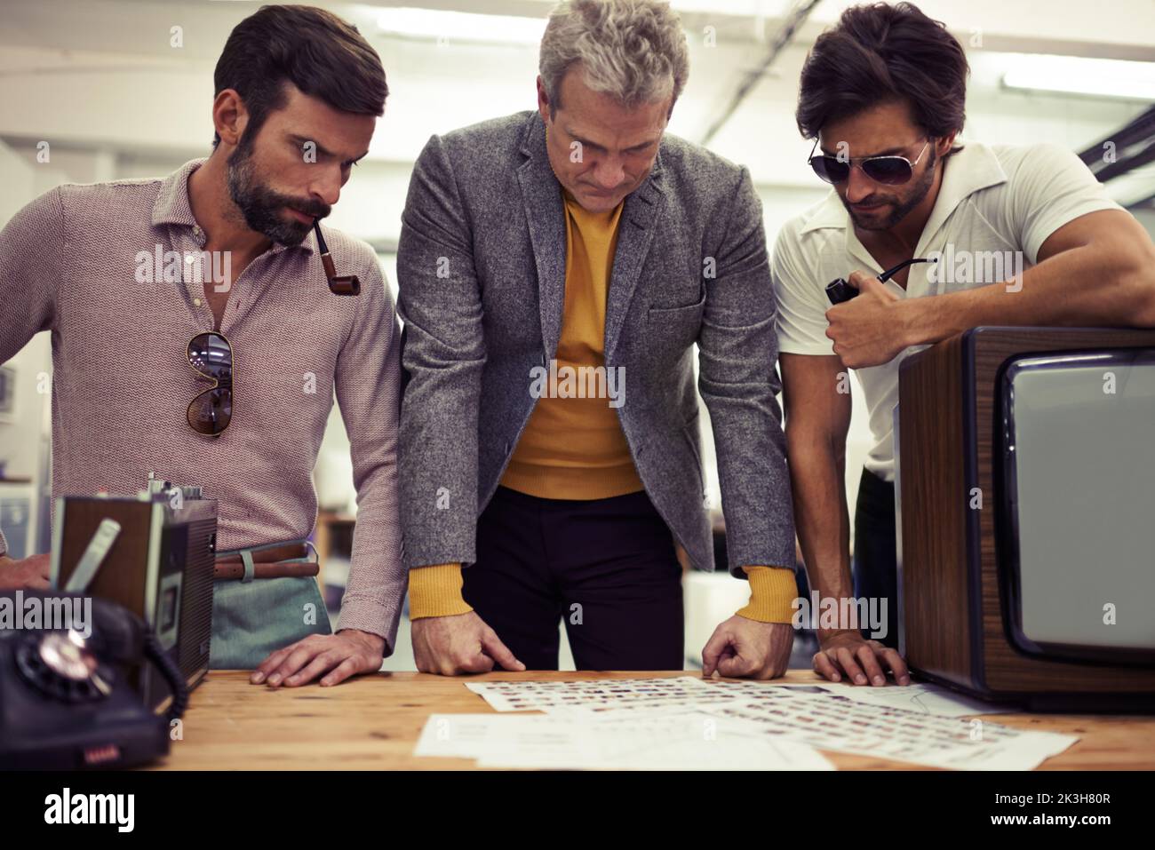 Ecco le nostre scelte... tre designer rivestiti di abbigliamento retrò 70s che lavorano insieme a un progetto. Foto Stock