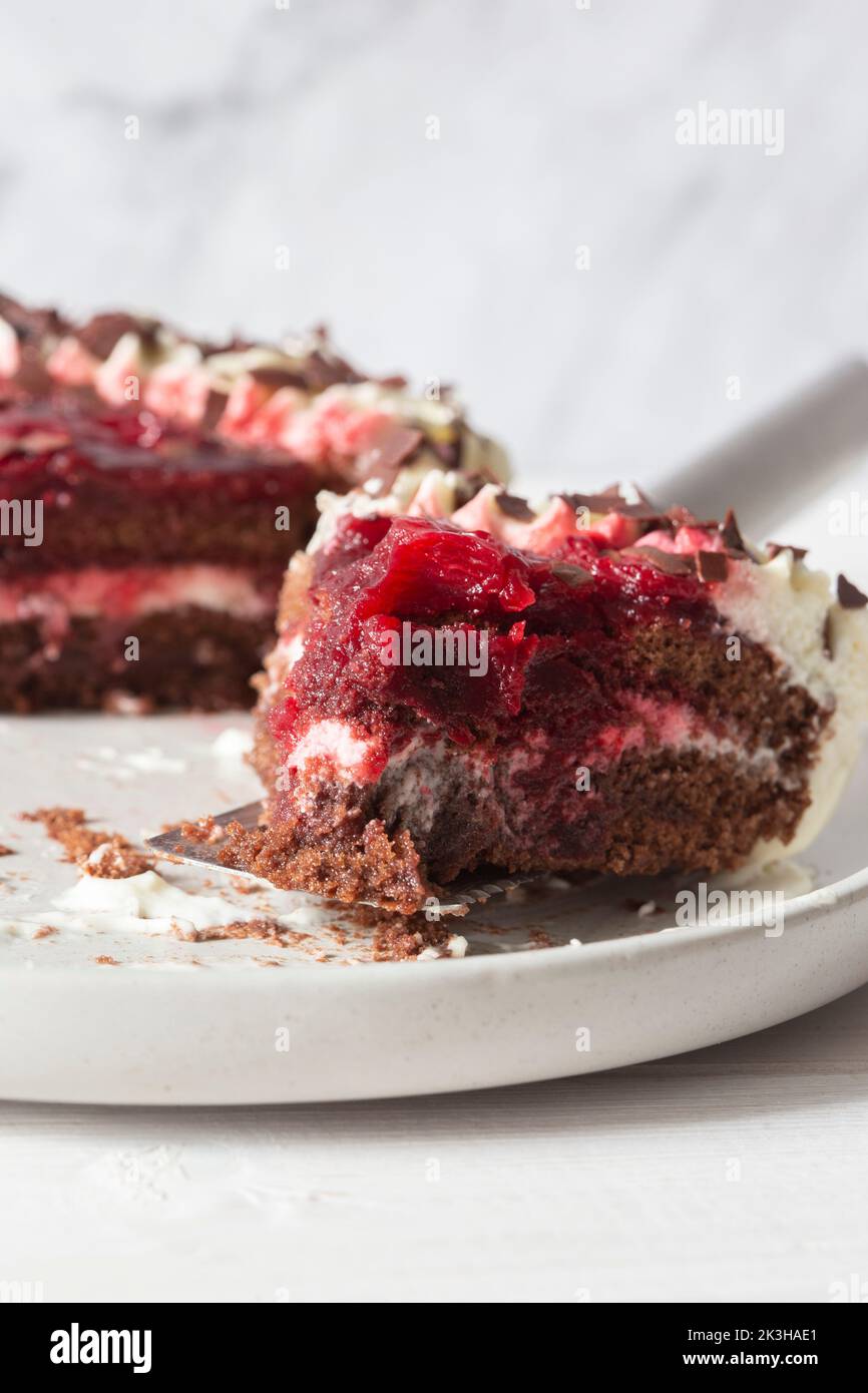 Dessert di gateaux della foresta nera, in parte mangiato, su un piatto di gres grigio Foto Stock