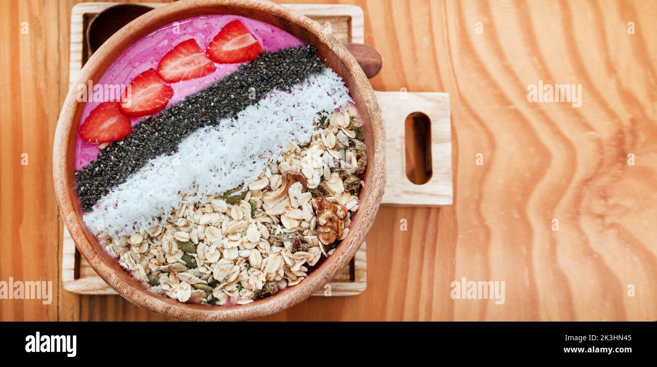 Deliziosa colazione sana, ciotola di frullato di fragole con muesli, frutta, semi di chia e cocco, un'immagine estetica su sfondo chiaro. Foto Stock