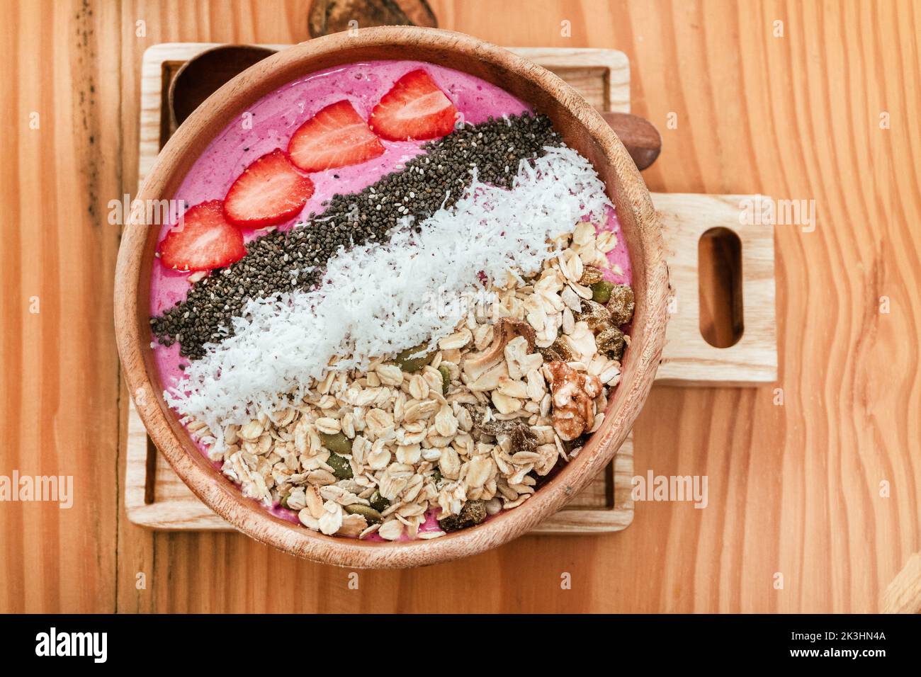 Deliziosa colazione sana, ciotola di frullato di fragole con muesli, frutta, semi di chia e cocco, un'immagine estetica su sfondo chiaro. Foto Stock