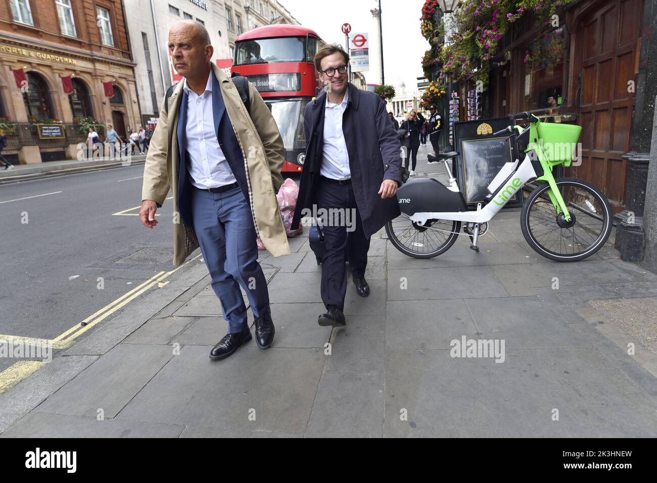 Londra, Inghilterra, Regno Unito. Due uomini che camminano lungo Whitehall. Londra bus e noleggio biciclette Lime Foto Stock