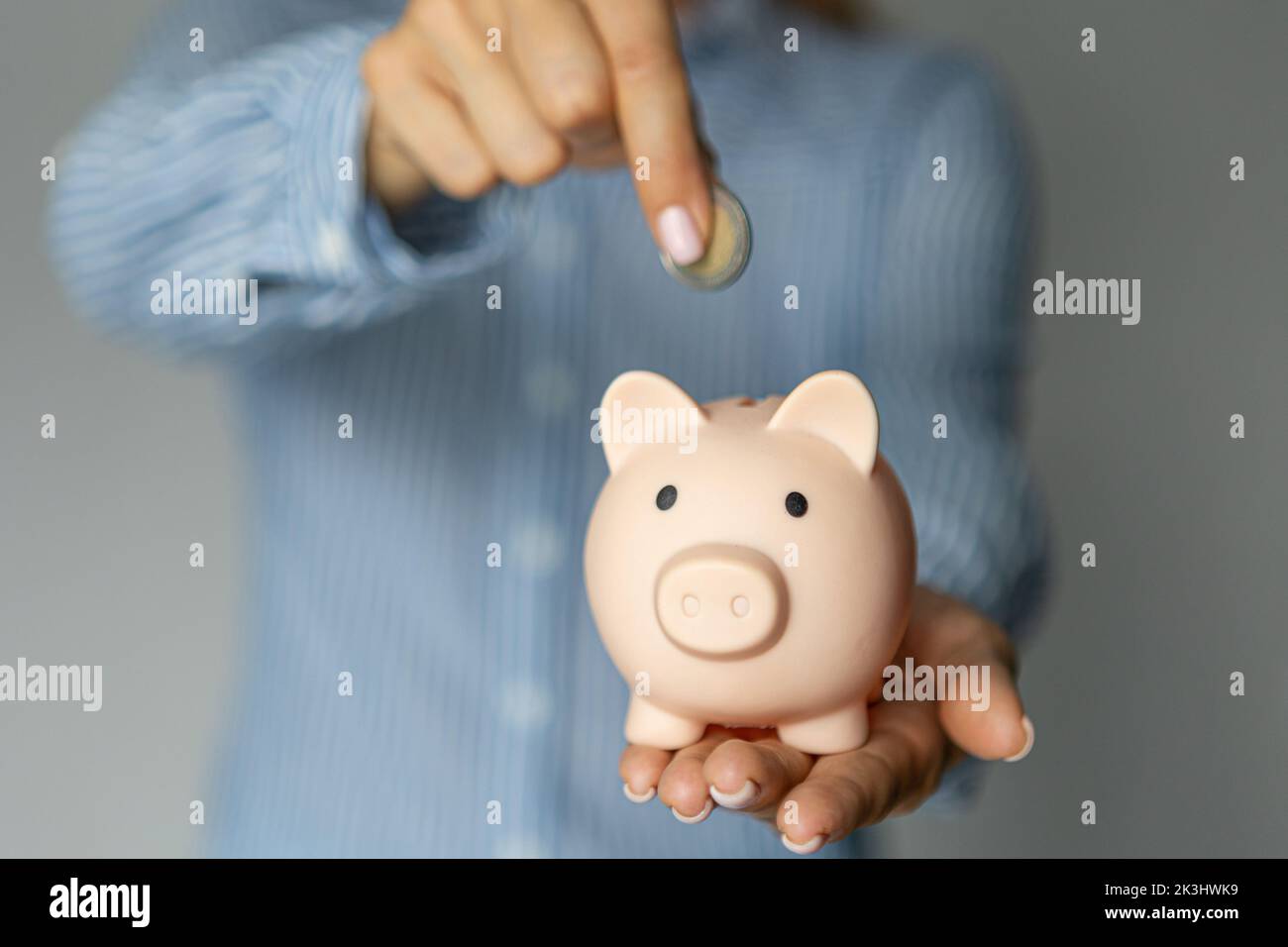 le mani femminili hanno messo i soldi dell'euro in una banca rosa del piggy. Il concetto di risparmio di denaro o di risparmio, investimento Foto Stock
