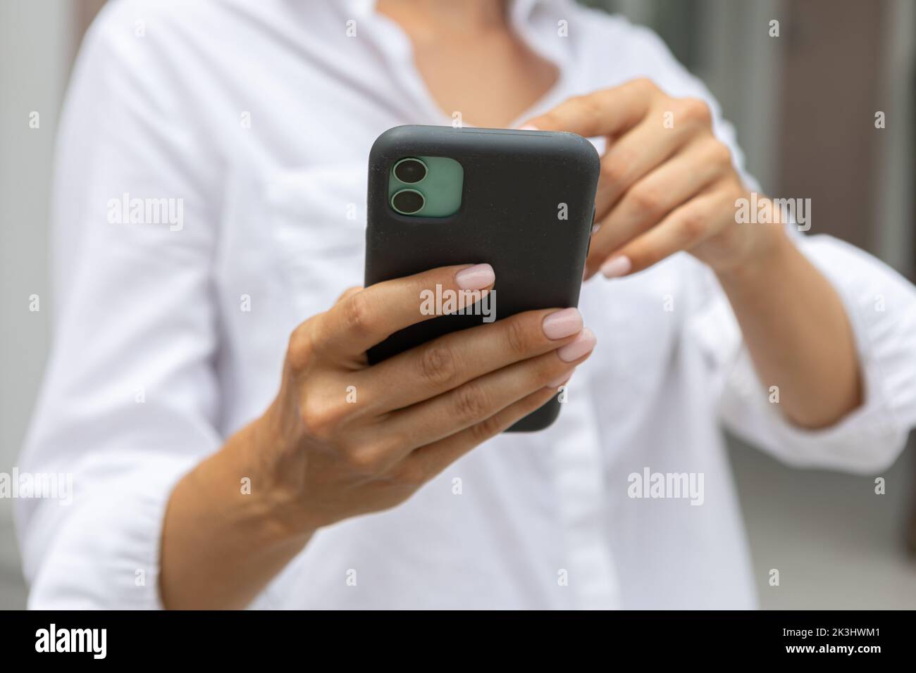 le mani femminili tengono un telefono cellulare moderno per strada. notizie, istruzione, app moderna, ordine di acquisto, lavoro online Foto Stock