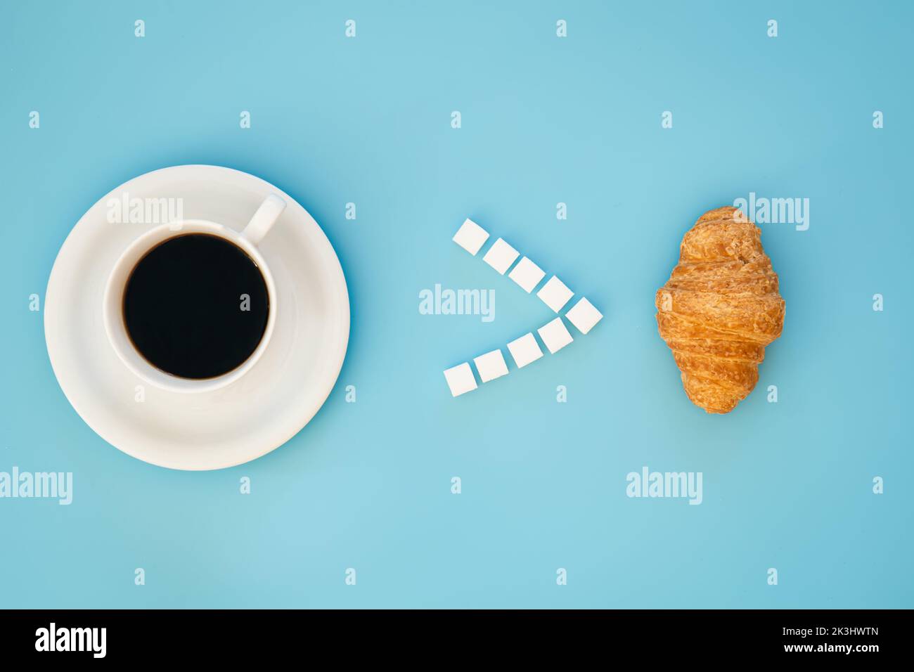 Una tazza di caffè e un croissant su sfondo blu, piatto. Foto Stock