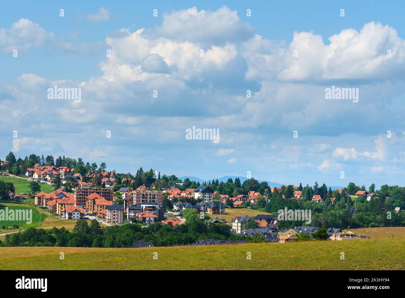 Bellissimo paesaggio pittoresco della regione di Zlatibor con case in stile architettonico distintivo sparse sulle verdi colline nelle soleggiate giornate estive Foto Stock