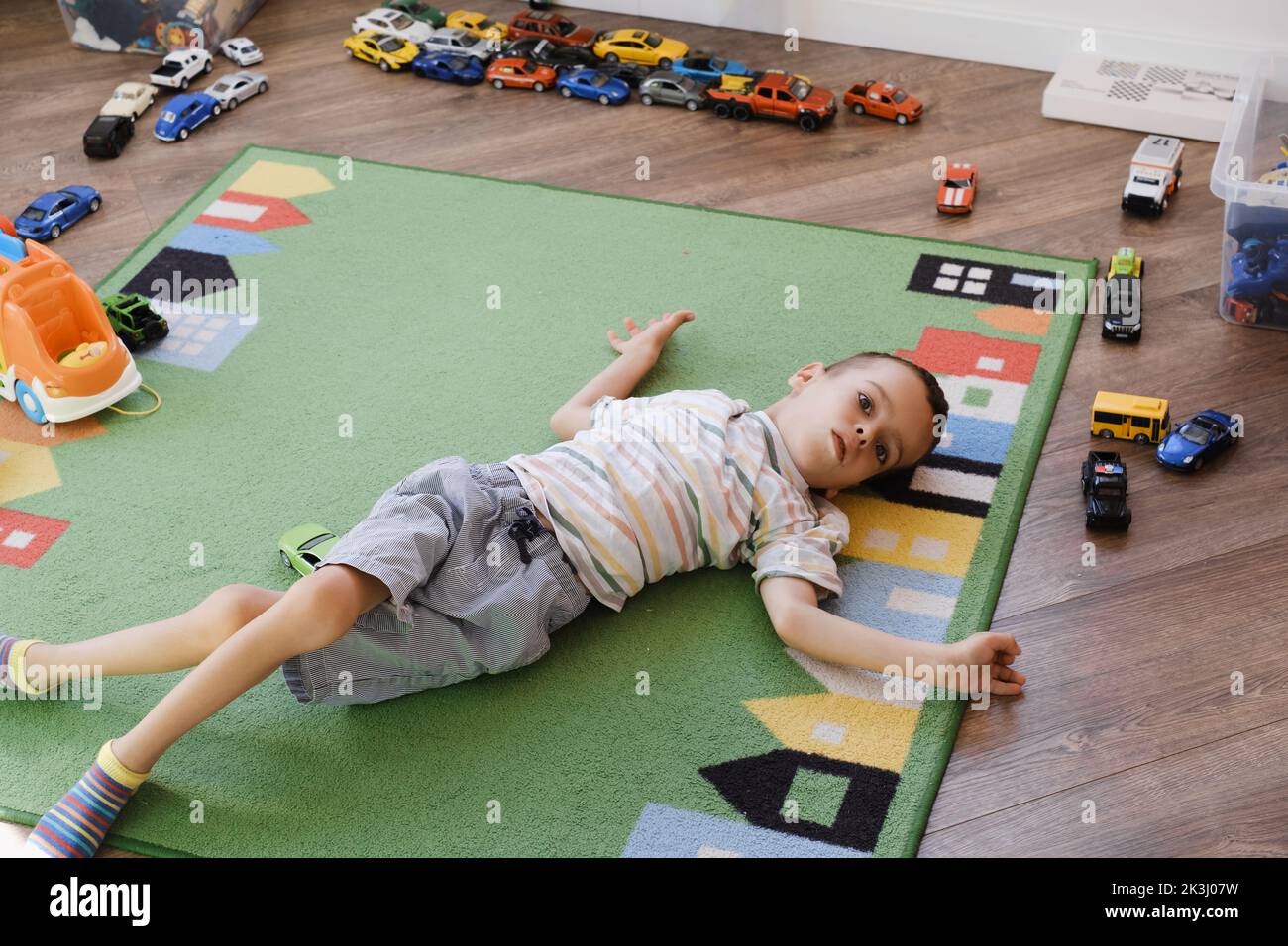 Bambino con disabilità della paralisi cerebrale che gioca sul tappeto, divertendosi. Bambino che ha disturbi fisici e mentali giochi sensoriali e la terapia a casa sul Foto Stock