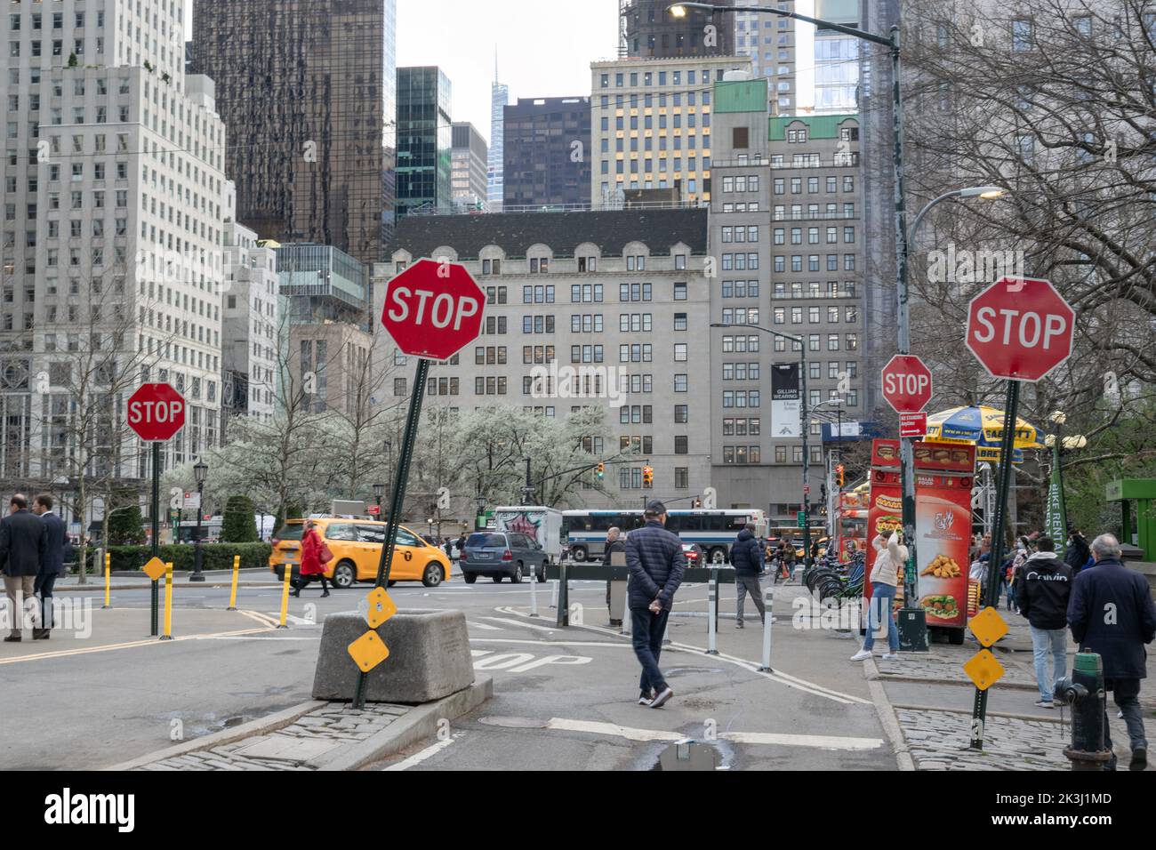 Persone, auto, taxi giallo fuori da Central Park e andare a Grand Army Plaza di fronte a 4 stop segni Foto Stock