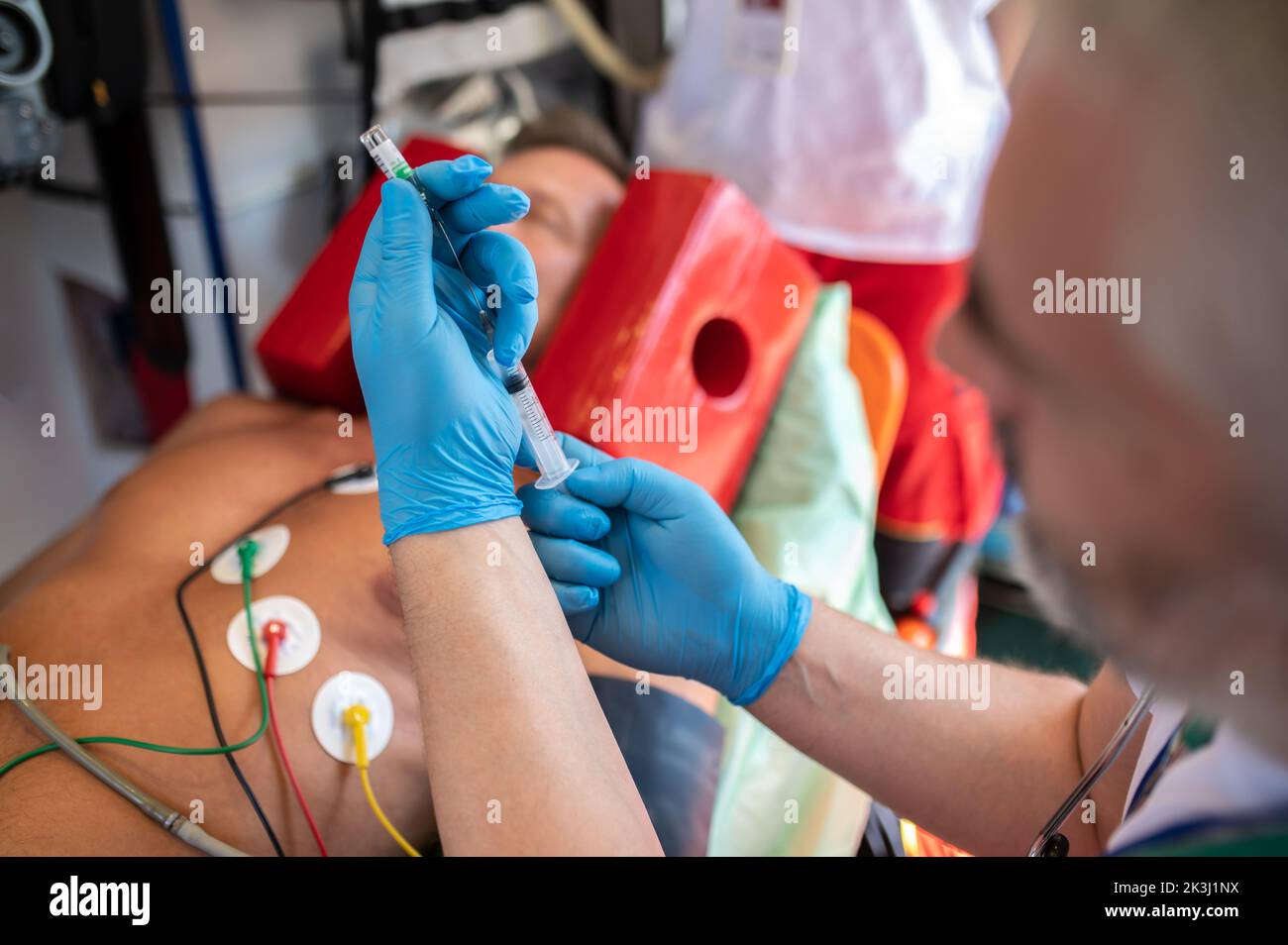 Medico di ambulanza che si prepara a somministrare un'iniezione ad un paziente Foto Stock