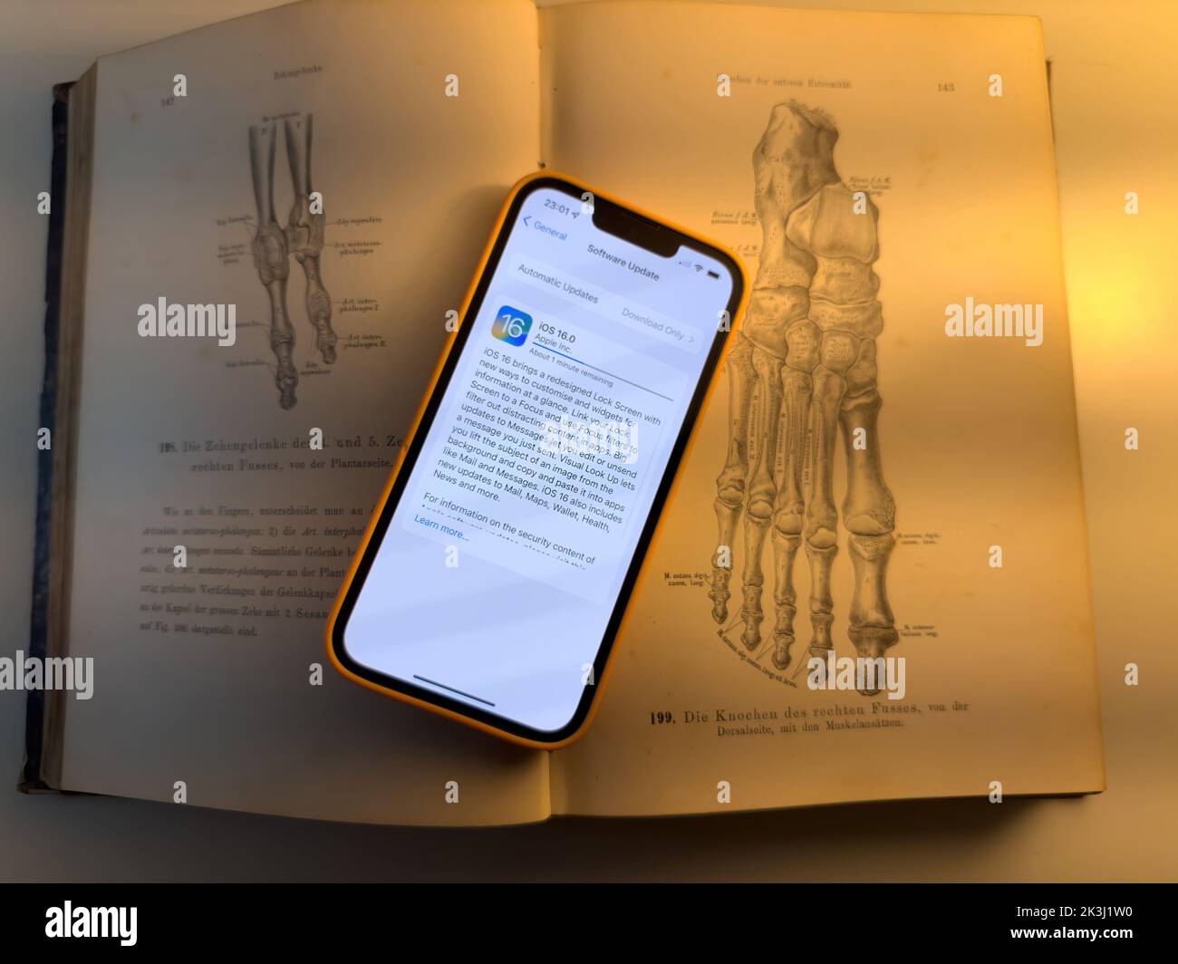 Parigi, Francia - 17 settembre 2022: Aggiornamento di Apple computer iphone 13 Pro aggiornamento processo al nuovo sistema operativo iOS 16 - telefono posto sopra il vecchio libro anatomia Foto Stock