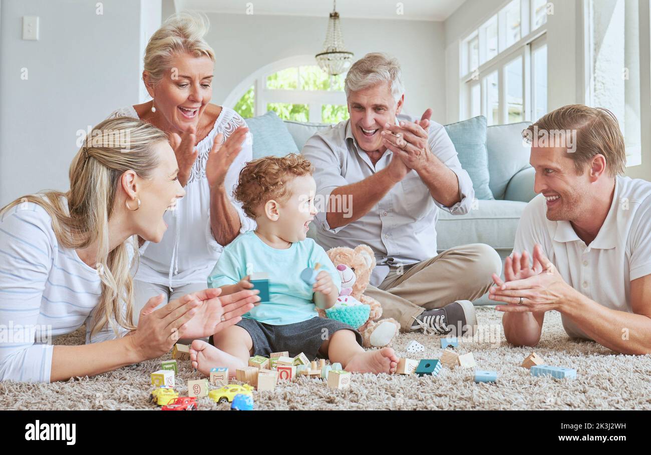 La famiglia, le mani e il bambino che giocano con i giocattoli mentre si siedono sul pavimento del soggiorno. Amore, cura e persone felici che incoraggiano lo sviluppo del bambino Foto Stock