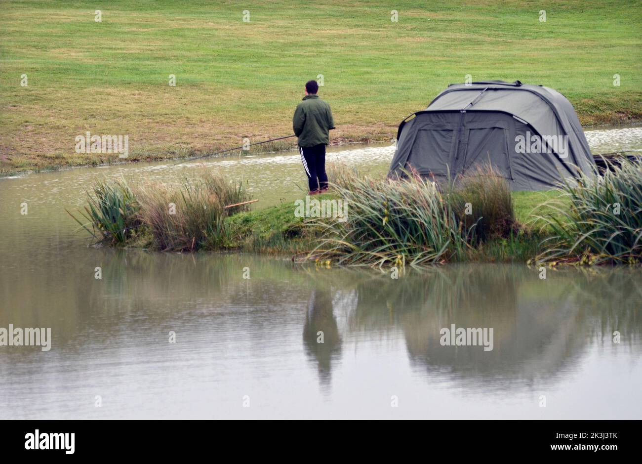 giovane uomo che pesca nel lago di carpa con pernottamento tenda bivia Foto Stock