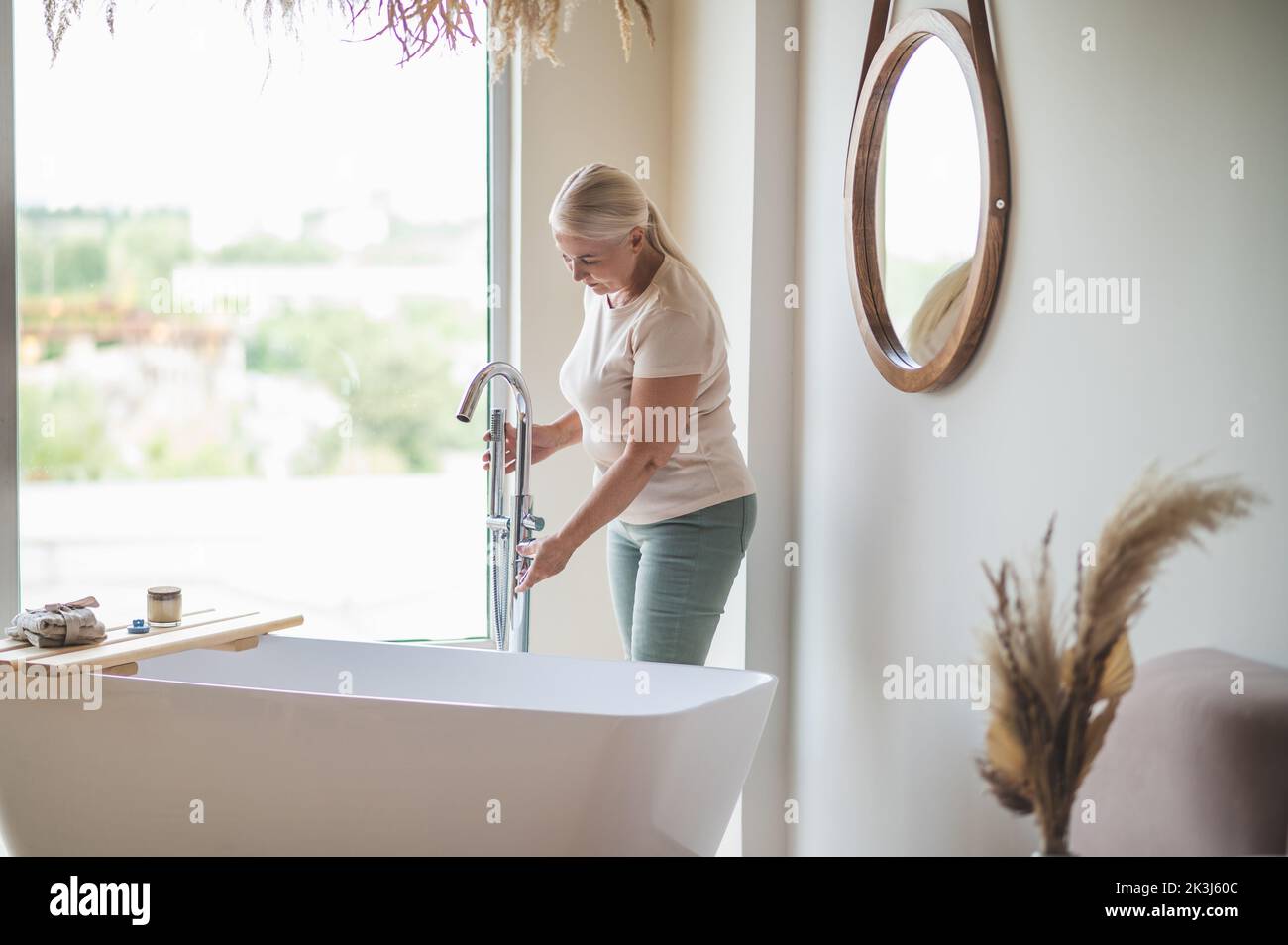 Donna adulta caucasica che apre il rubinetto cromato Foto Stock
