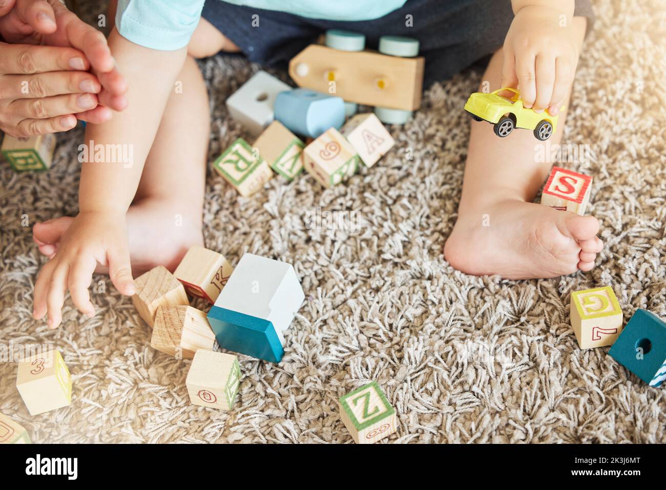 Primo piano dell'apprendimento del bambino con i giocattoli, il puzzle di blocco ed il treno per aiutare la coordinazione dell'occhio della mano sul pavimento in casa. I bambini imparano con i giochi educativi sopra Foto Stock