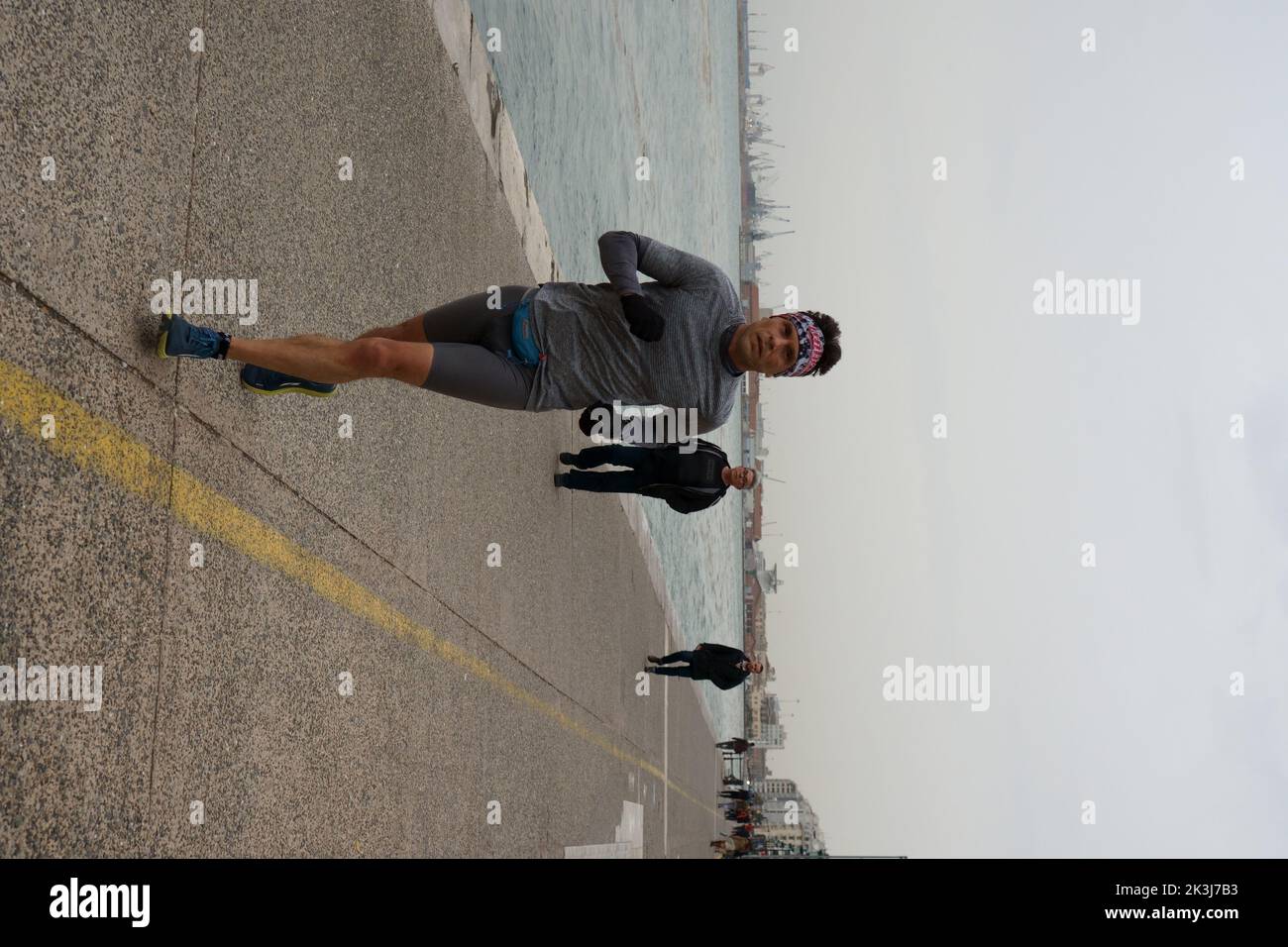 Un colpo verticale di un corridore maschio nelle strade dei porti di Salonicco con persone che camminano sullo sfondo Foto Stock