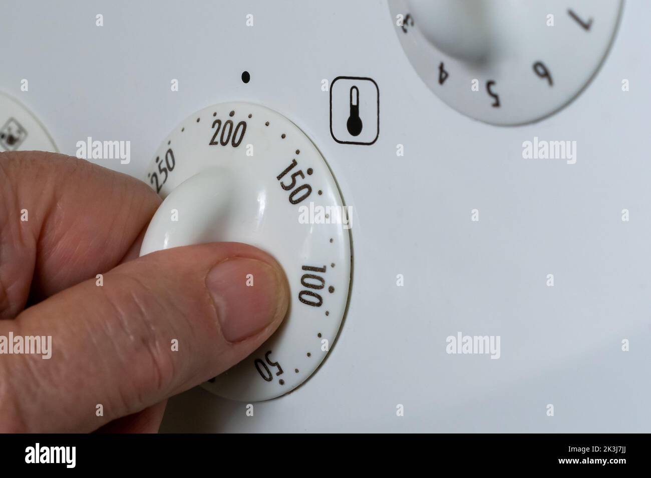 La mano regola la temperatura della nuova stufa elettrica, risparmiando energia Foto Stock