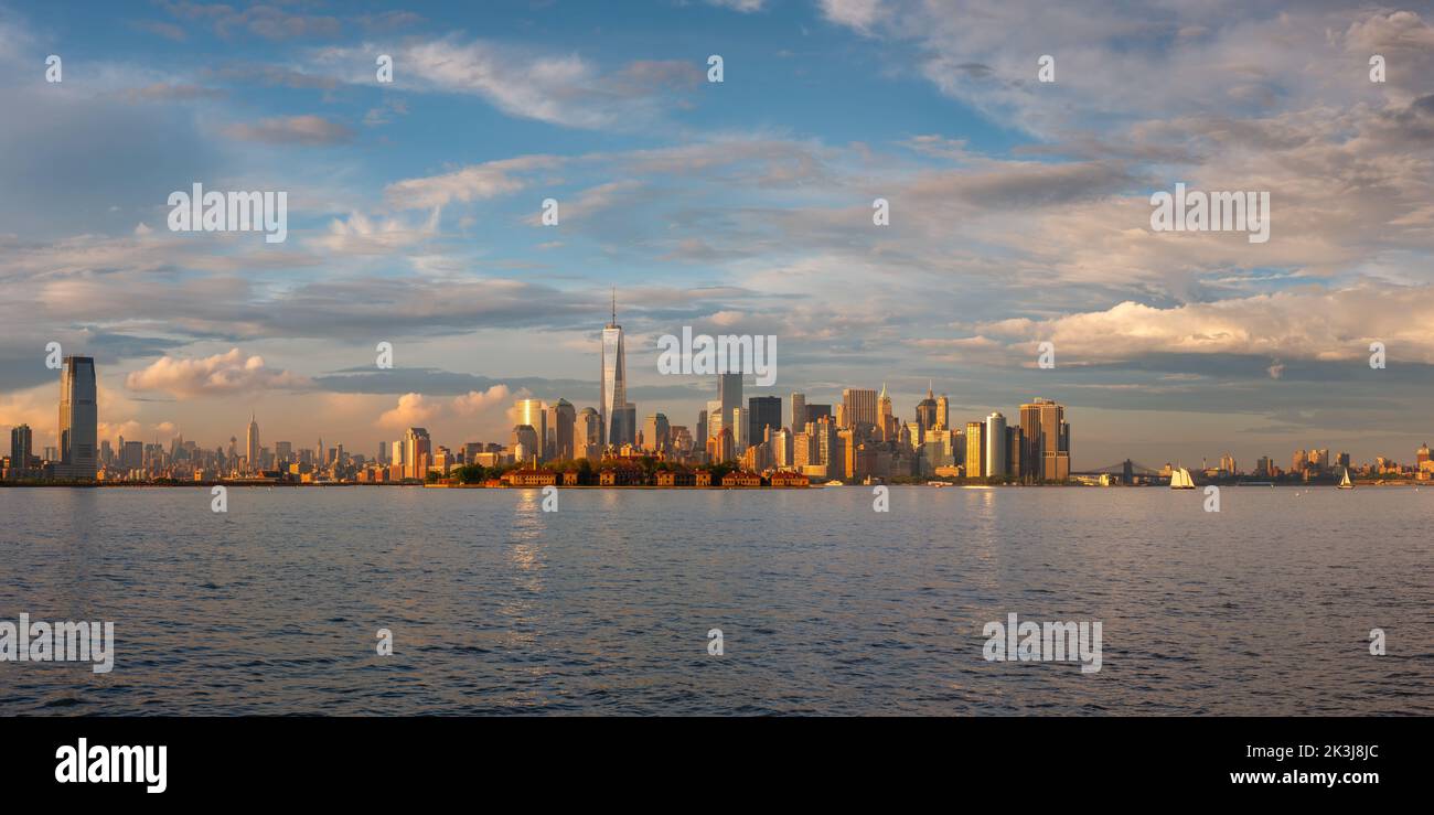 Grattacieli del quartiere finanziario di New York City Lower Manhattan (World Trade Center) ed Ellis Island al tramonto dal porto di New York Foto Stock