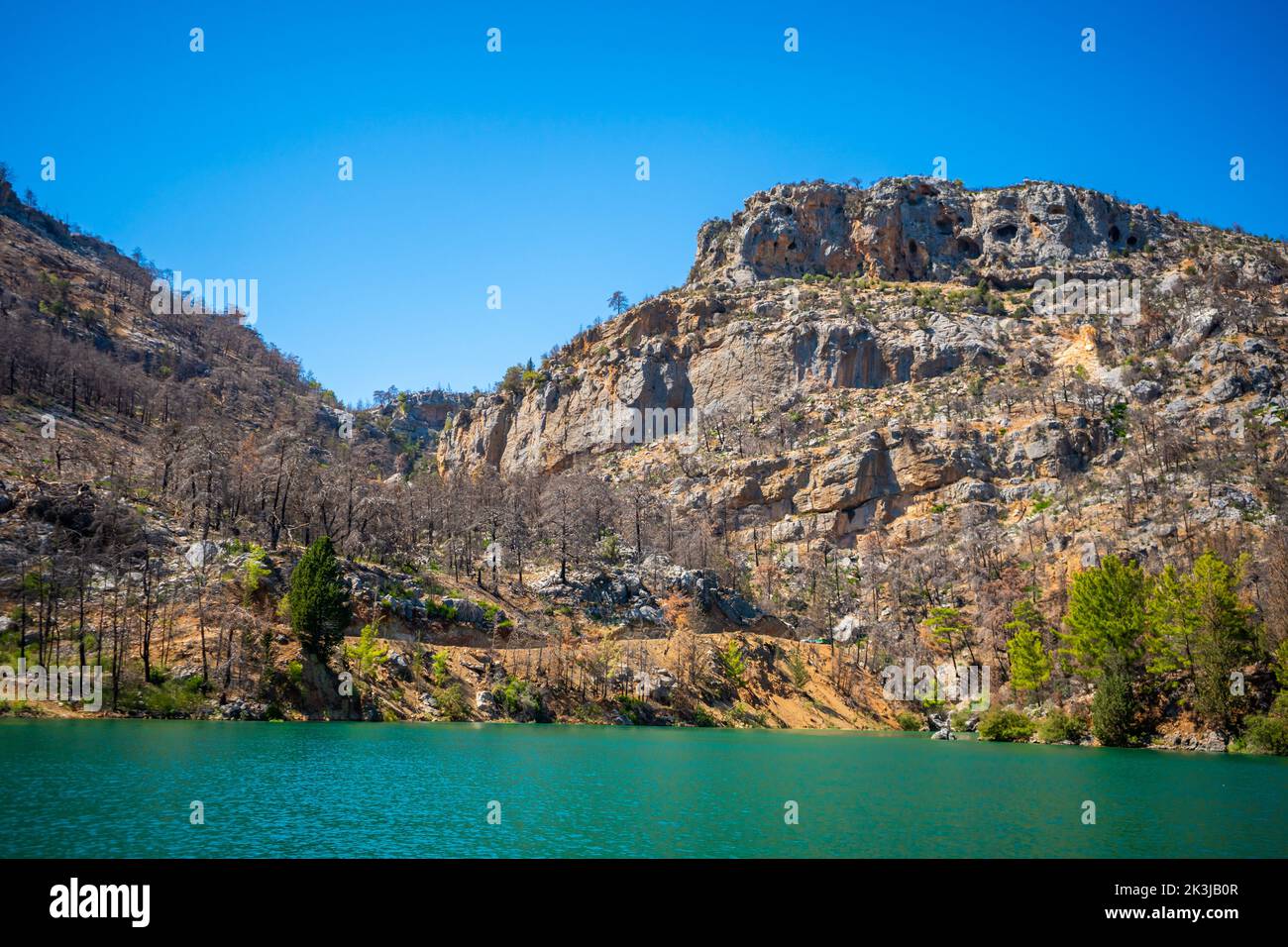 Vista delle rocce vicino al lago blu dopo l'incendio della foresta nelle montagne turche Foto Stock