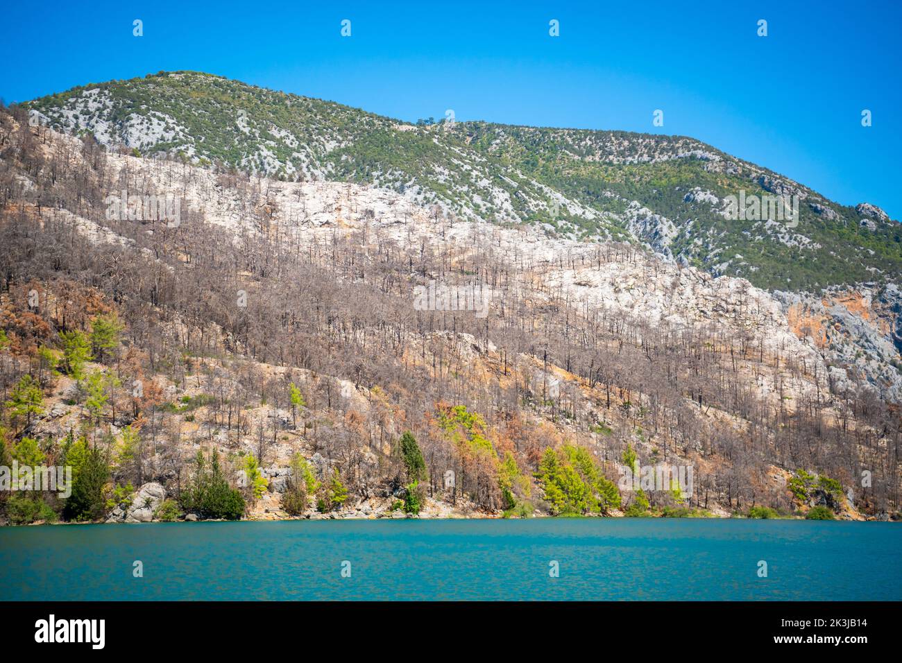 Vista delle rocce vicino al lago blu dopo l'incendio della foresta nelle montagne turche Foto Stock