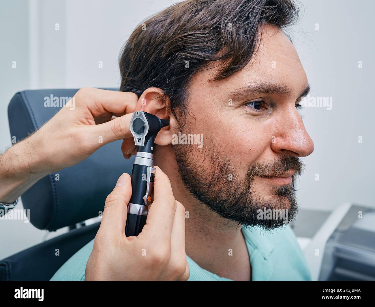 Uomo adulto durante l'esame dell'orecchio presso la clinica uditiva. Audiologo che esamina l'orecchio di un paziente maschio utilizzando un otoscopio, primo piano Foto Stock