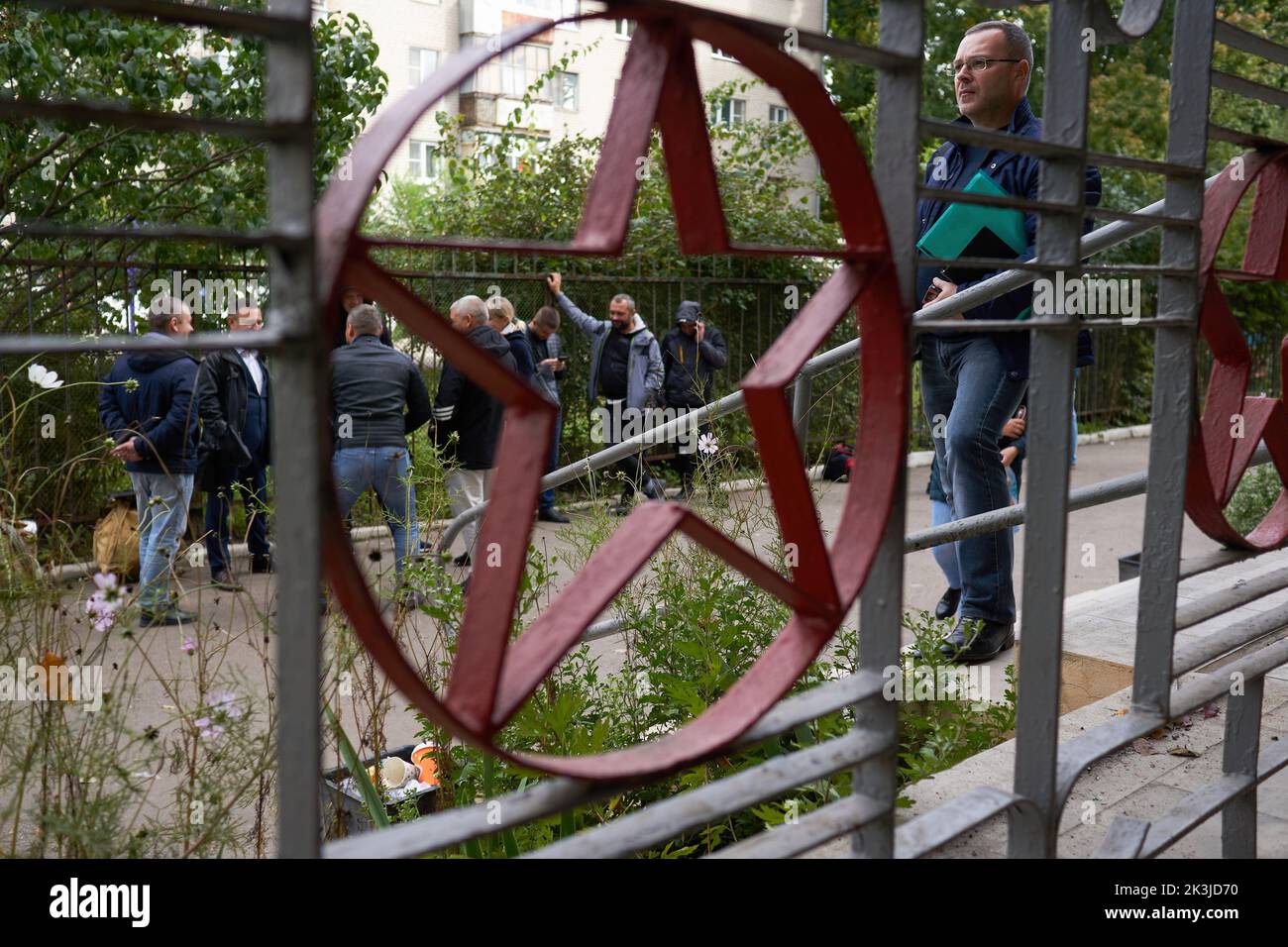 Una grata con una stella sovietica e uomini davanti all'ufficio militare durante la mobilitazione a Voronezh. Il 21 febbraio, il presidente russo Vladimir Putin ha firmato un decreto sulla cosiddetta mobilitazione parziale. Secondo questo documento, quasi tutti gli uomini di età compresa tra i 18 e i 65 anni possono essere chiamati al servizio militare. Alcune di queste persone possono essere inviate direttamente alla guerra con l'Ucraina. Insieme alle proteste contro la mobilitazione, molti cittadini russi hanno accolto con entusiasmo questo decreto. A Voronezh, quasi ogni giorno, gruppi di persone si riuniscono negli uffici militari di registrazione e di arruolamento, pronti a Foto Stock