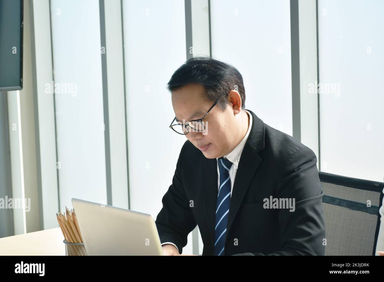 Buon uomo d'affari asiatico che usa un computer portatile in ufficio Foto Stock