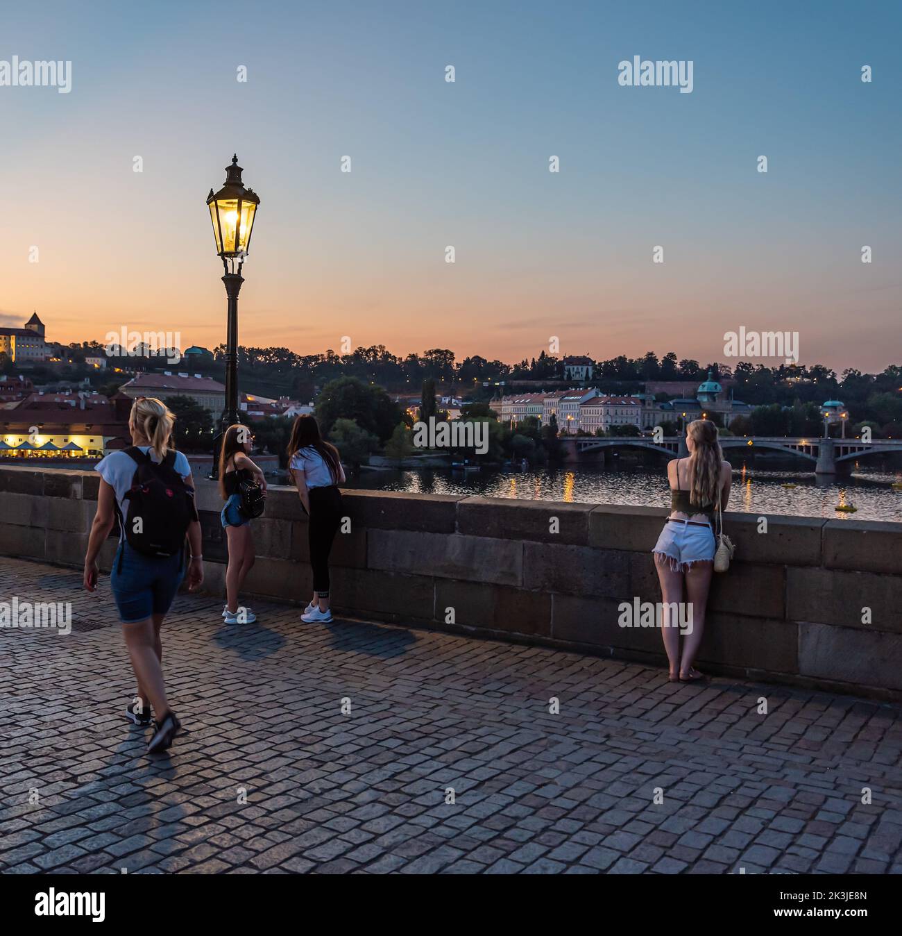 Praga - Repubblica Ceca - 08 01 2020 turisti in abiti estivi a piedi sul ponte Carlo durante una notte d'estate con un cielo colorato Foto Stock