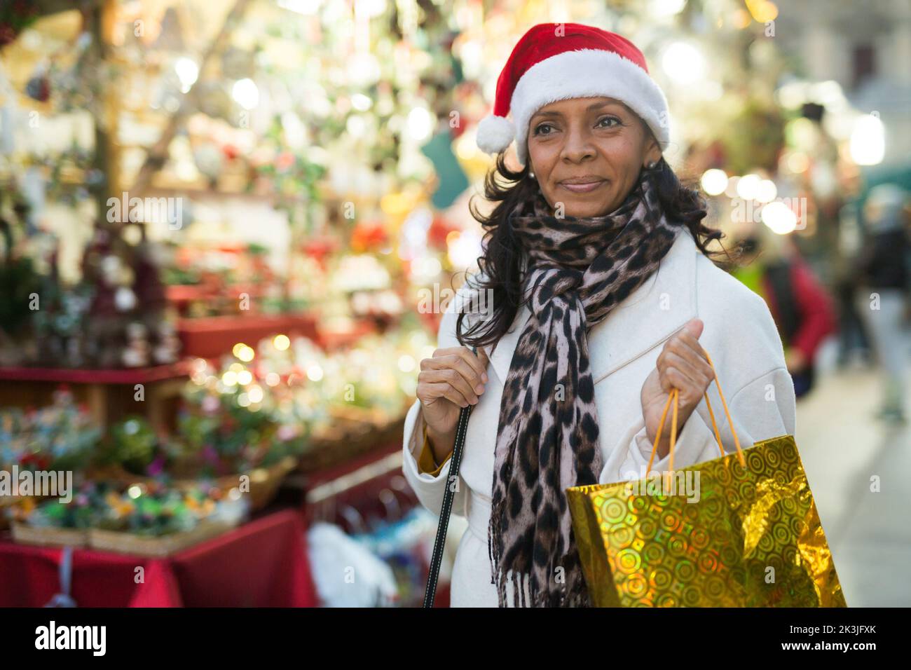 Donna con i sacchetti di shopping che sorridono emozionalmente alla fiera di Natale Foto Stock