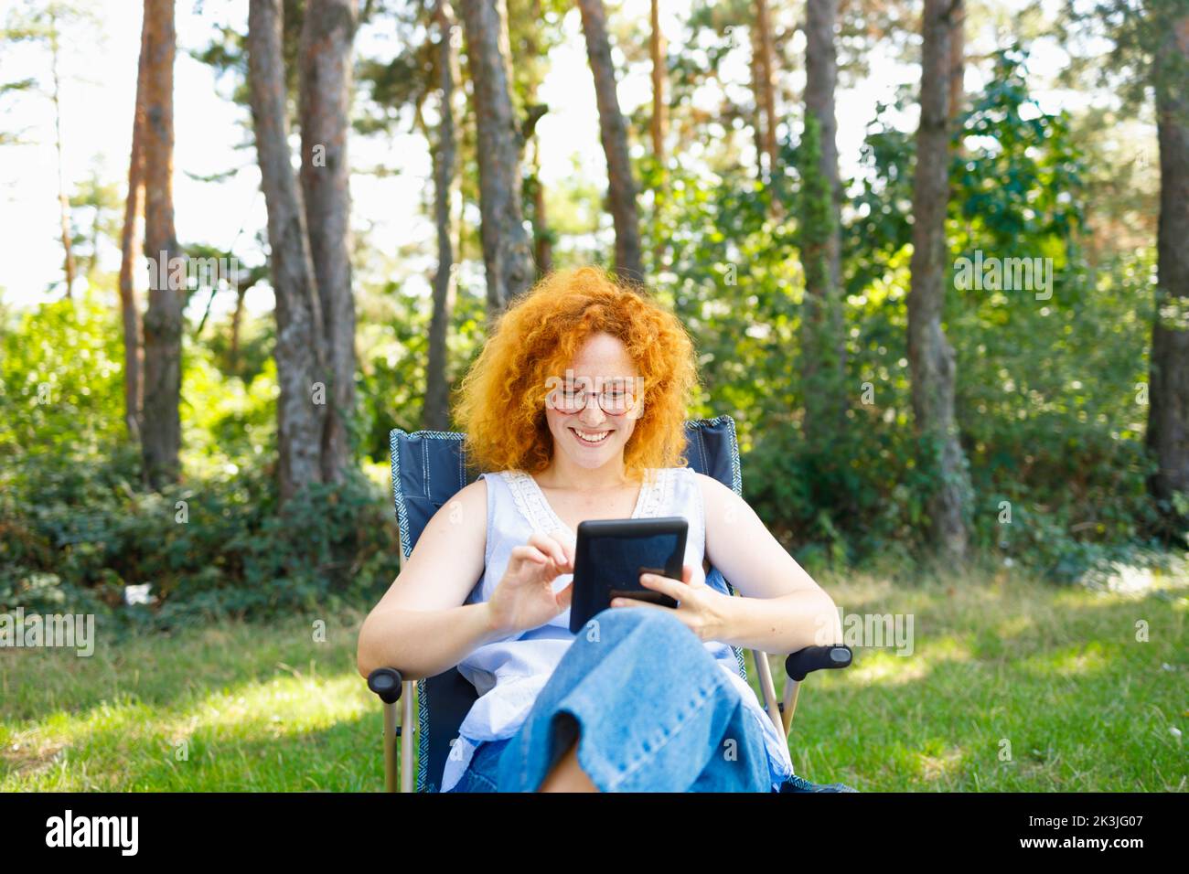 Una donna seduta nella natura e navigando in internet e acquistando per il Black Friday Foto Stock