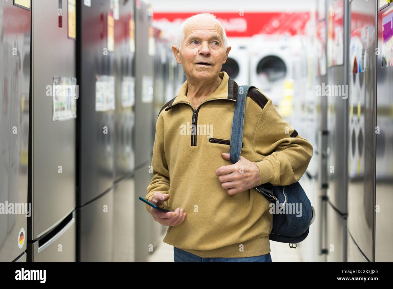 anziani uomo pensionato grigio guardando frigorifero al banco in showroom di elettrodomestici ipermercato reparto Foto Stock