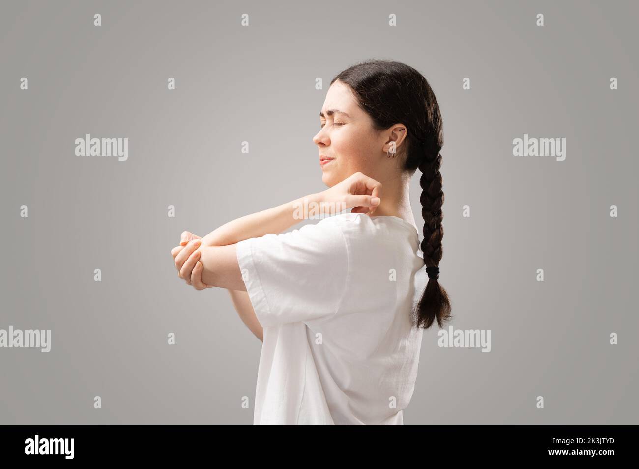 La giovane donna sofferente con le code di piggy scuro tiene il gomito con la mano, provando dolore. Infiammazione delle articolazioni. Il concetto di assicurazione di healt Foto Stock