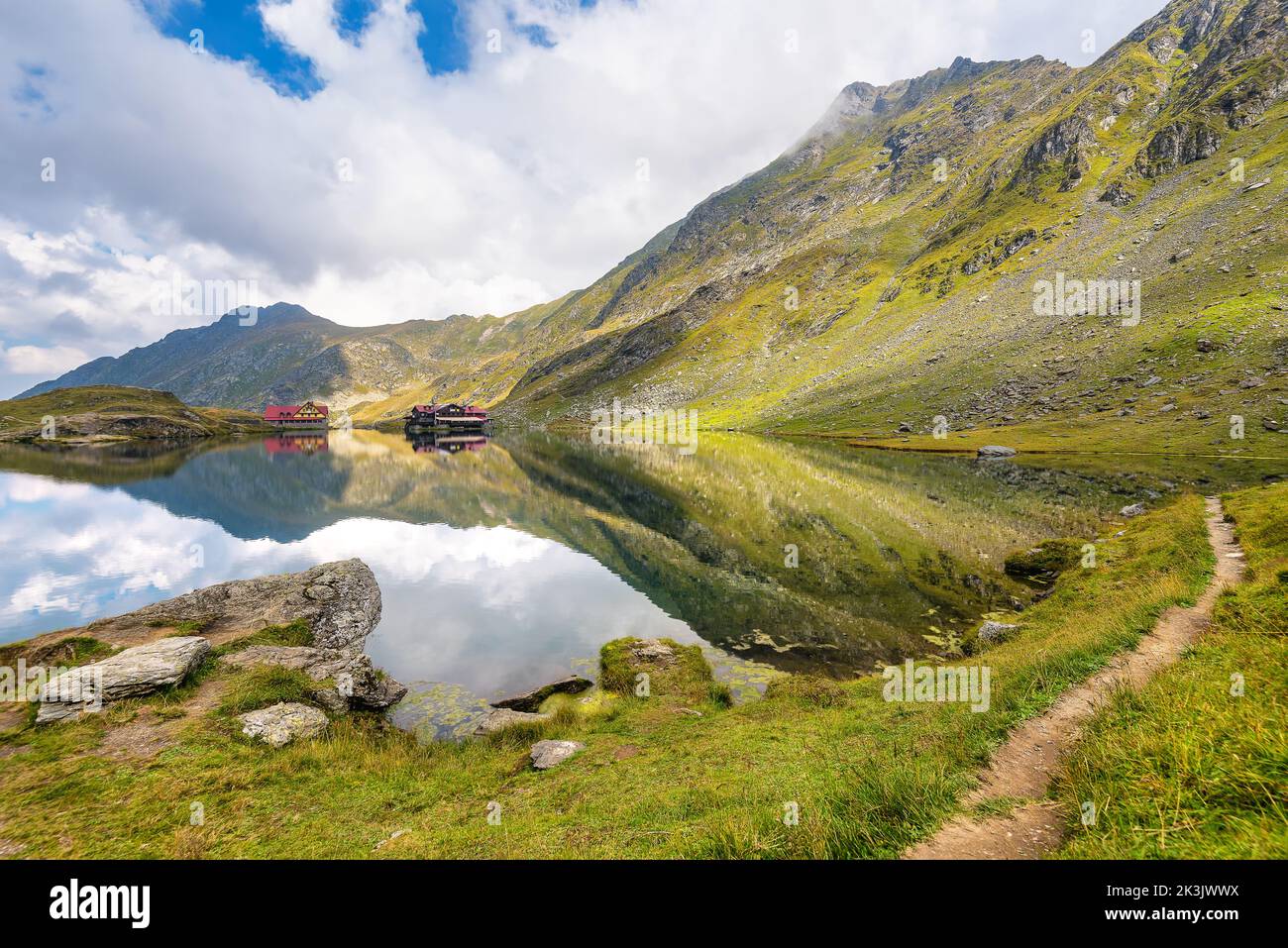 La vista panoramica delle Alpi della Transilvania si rifletteva sull'alta quota del lago Balea in Romania contro le drammatiche nuvole tempestose Foto Stock