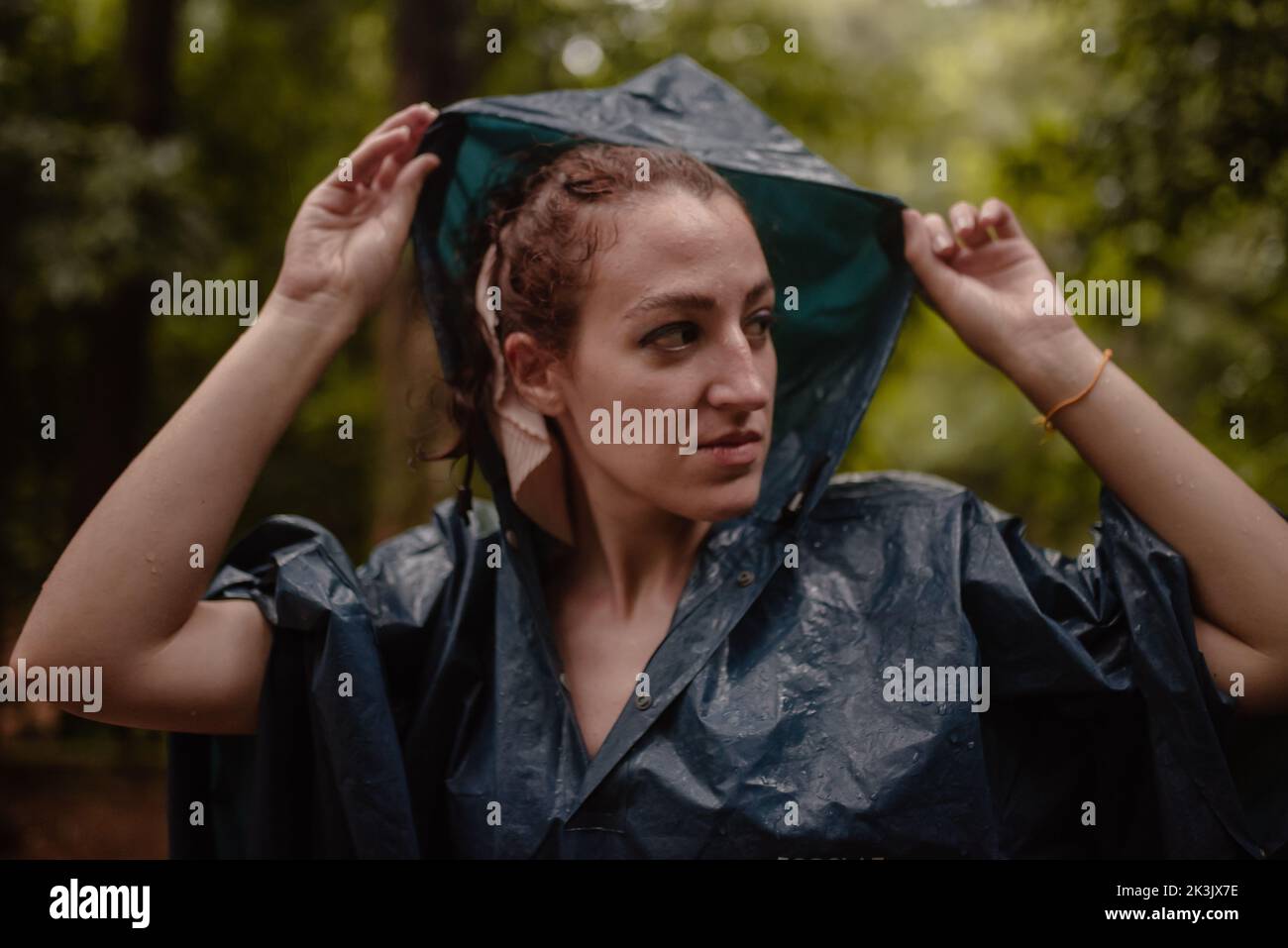 Donna in impermeabile in un giorno d'autunno che aggiusta il suo cappuccio. Foto Stock