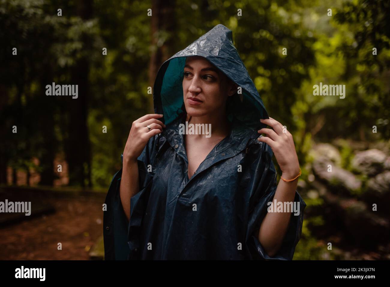 Donna in impermeabile in un giorno d'autunno che aggiusta il suo cappuccio. Foto Stock