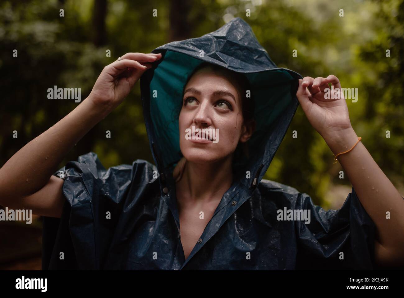 Donna in impermeabile in un giorno d'autunno che aggiusta il suo cappuccio. Foto Stock