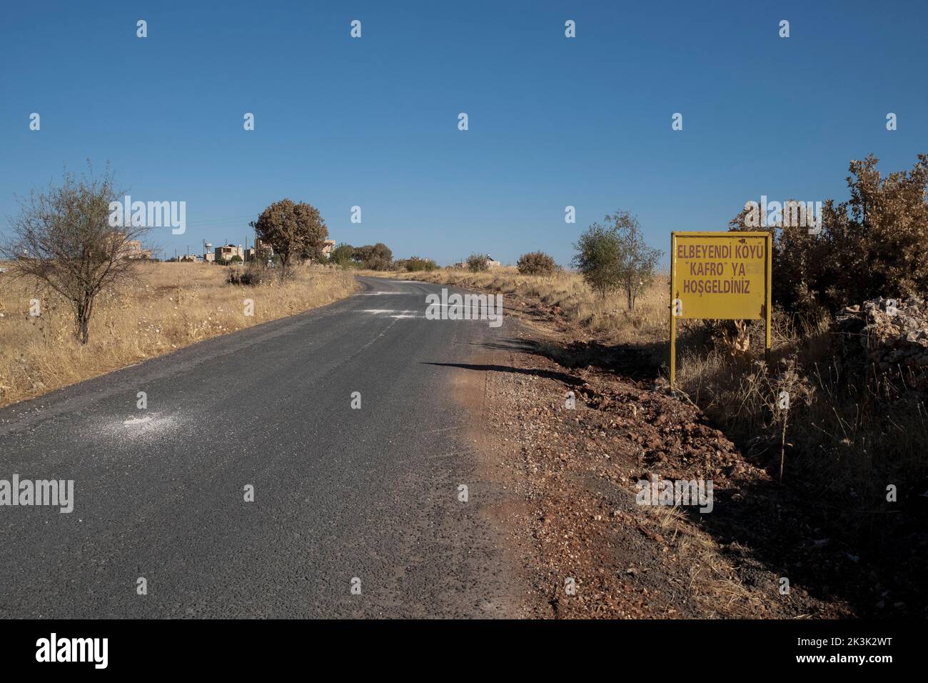 Vista di un cartello di 'Benvenuto' accanto alla strada all'entrata del Villaggio Kafro. C'è una pizzeria chiamata Kafro's Pizza nel villaggio di Elbegendi, nel quartiere Midyat di Mardin. La pizzeria prende il nome dal paese di Elbegendi, dove vivono gli assiri, sul monte Bagok. La pizzeria, il cui proprietario e personale sono assiri, accoglie decine di clienti ogni giorno a causa della sua posizione nel villaggio e le sue deliziose pizze. Nail Demir, il proprietario del posto, ha imparato a fare la pizza mentre vive in Europa e ha deciso di aprire la pizza di Kafro 10 anni fa nel villaggio dove è nato. Foto Stock