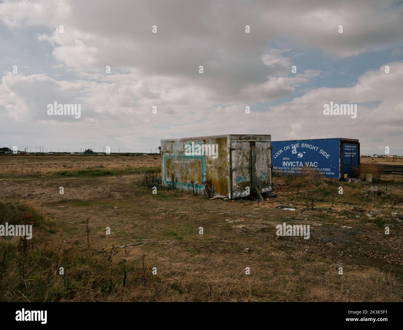 Guardate sul lato luminoso - vecchi container riproposti per immagazzinare reti da pesca e attrezzature da pesca su Dungeness Kent Inghilterra UK - strano paesaggio eccentrico Foto Stock