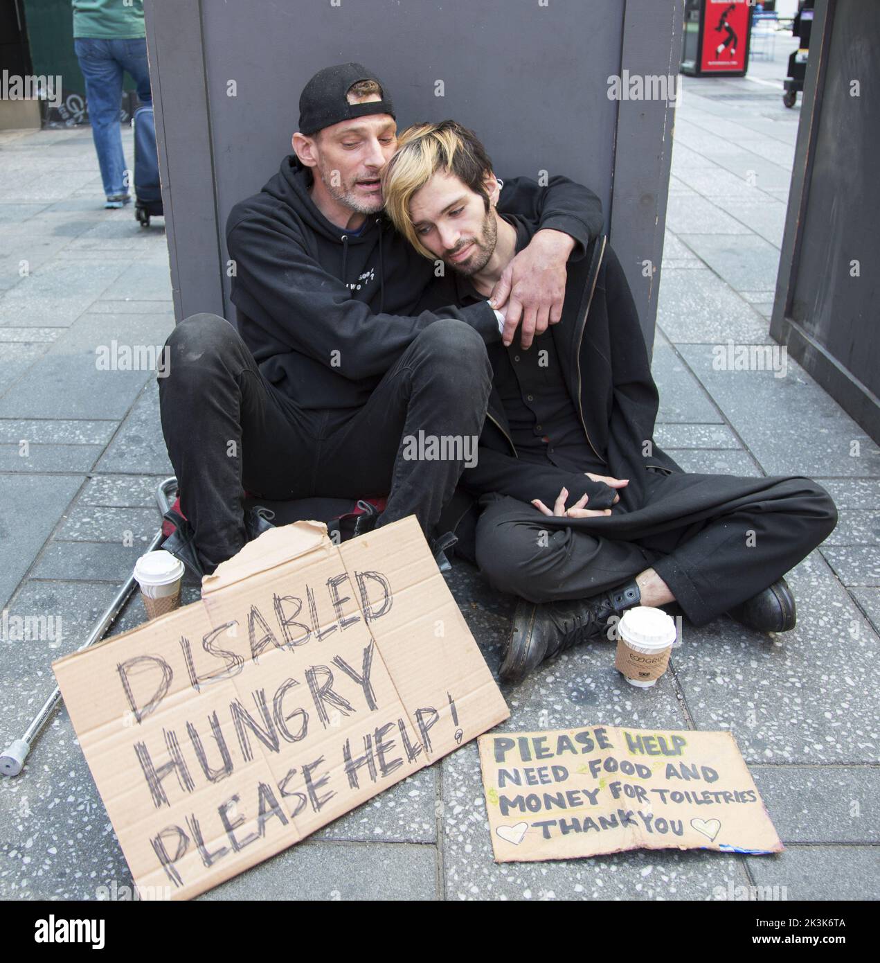 Un disabile senza tetto con un partner chiede aiuto seduto sul marciapiede nella zona di Times Square a New York City. Foto Stock