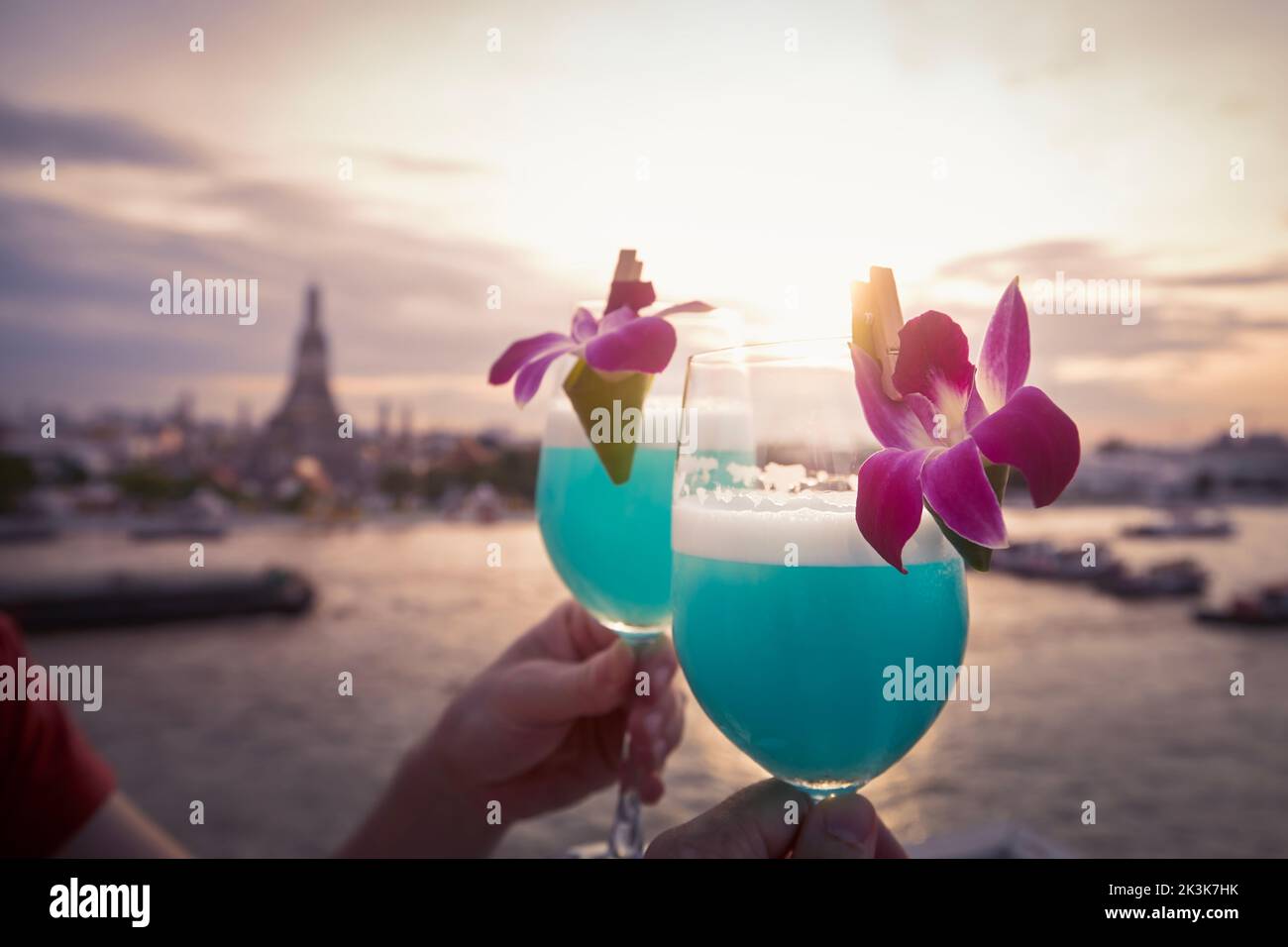 Cocktail con curacao blu. Coppia con bicchieri decorati davanti alla vista della città al tramonto. Bangkok, Thailandia Foto Stock