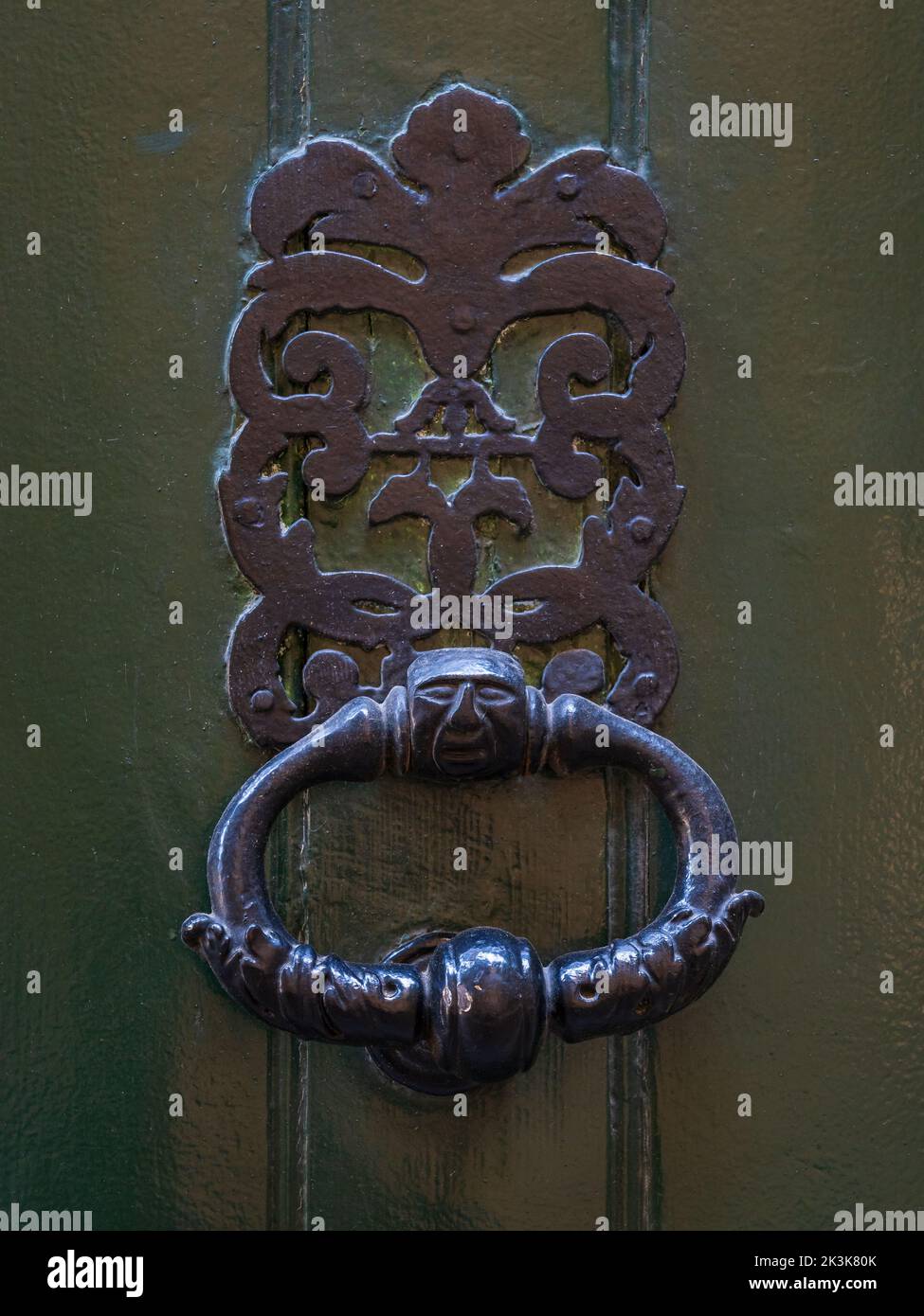 Vista in primo piano del tradizionale knoccer porta in ottone vintage con facciata stilizzata isolata su antica porta in legno verde bronzo, Montpellier, Francia Foto Stock