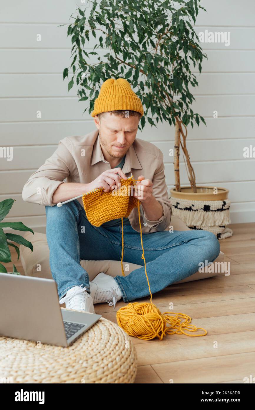 Uomo di mezza età che si maglia a casa. Progetto di Unione in corso. Uomo che impara un nuovo hobby Foto Stock