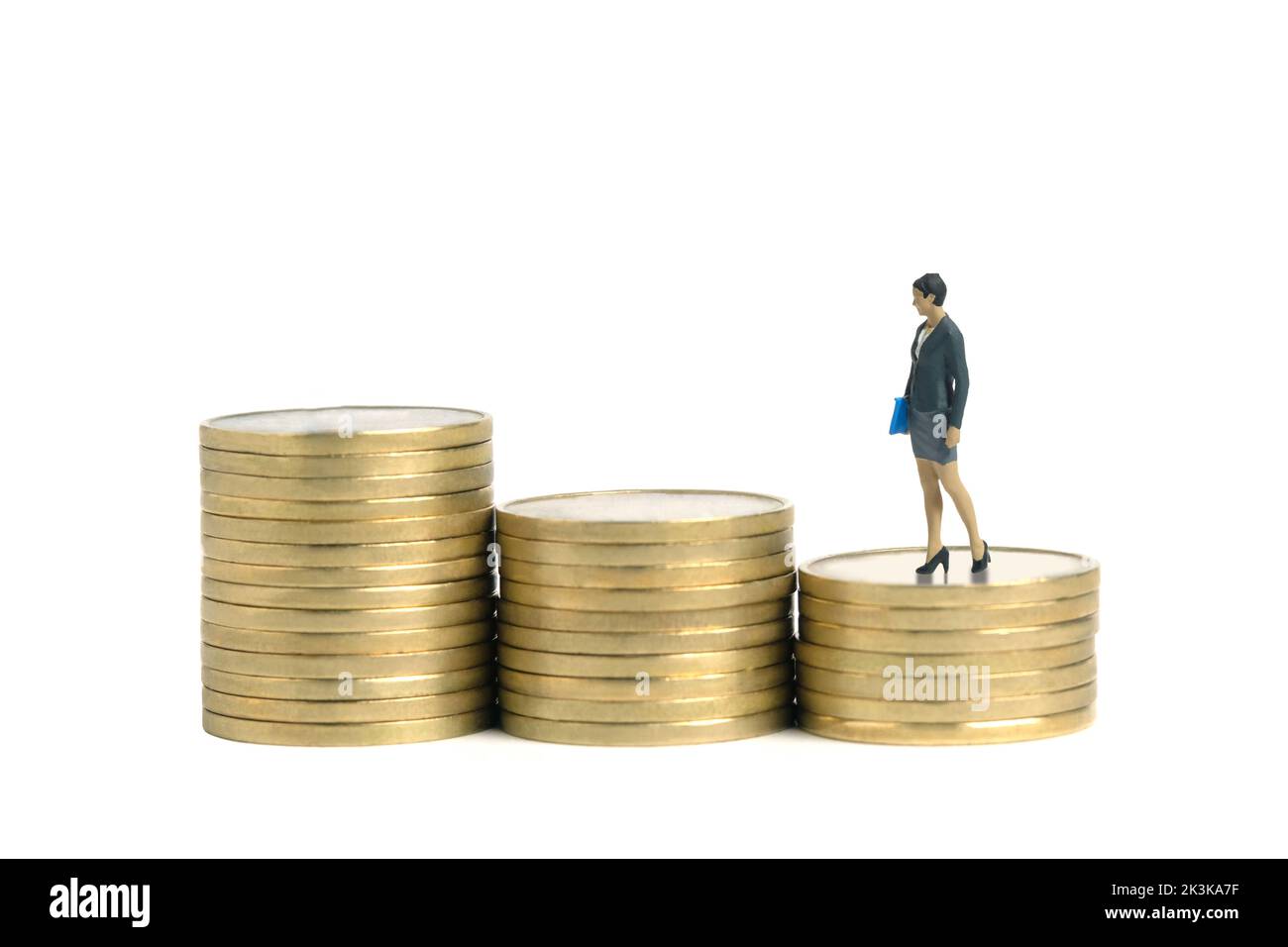 Fotografia di figura giocattolo delle persone in miniatura. Concetto di crescita salariale. Donna d'affari in piedi sopra la pila di soldi della moneta della scala. Isolato su sfondo bianco Foto Stock