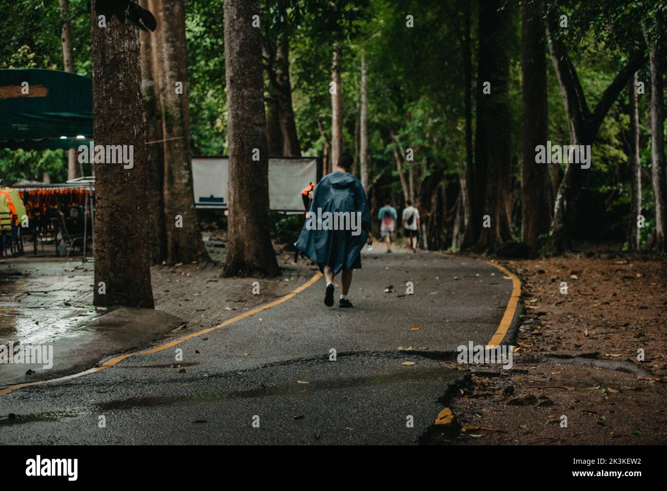 Uomo che indossa un impermeabile che cammina nel mezzo di una strada Foto Stock