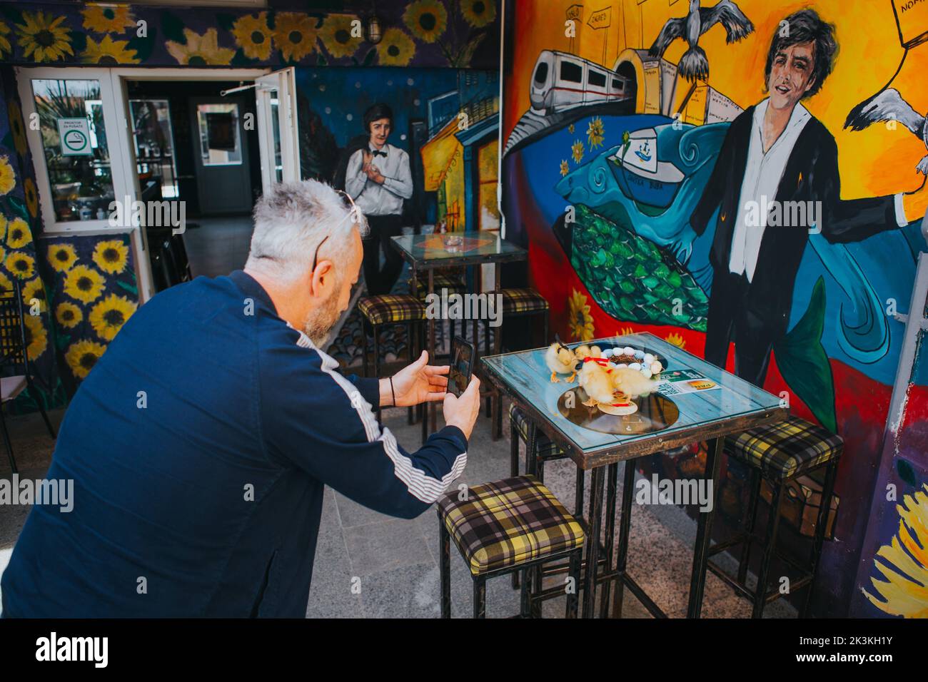 Un uomo anziano con capelli grigi che scatta foto di anatre in un caffè d'arte a Brcko, Bosnia ed Erzegovina Foto Stock