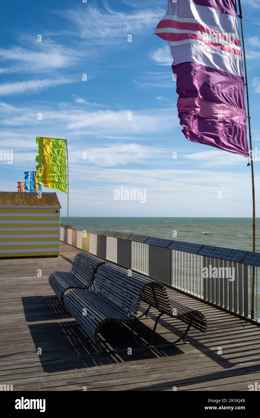 Una giornata ventosa con bandiere svolazzanti sul molo di Hastings Foto Stock