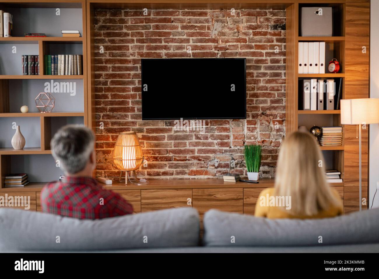 Riposati in coppia europea, guarda la tv con schermo vuoto nell'accogliente salotto interno, sul retro Foto Stock